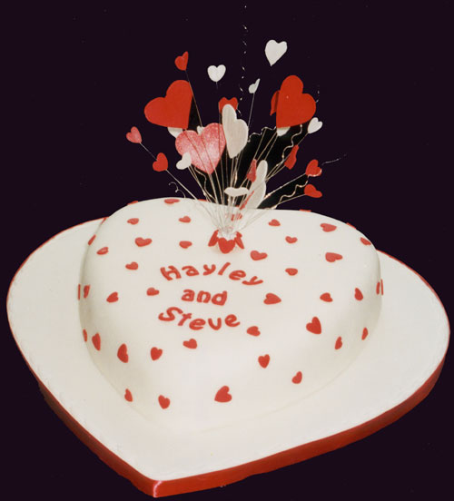 A heart-shaped madeira engagement cake is decorated with a sugar-crafted burst of hearts.