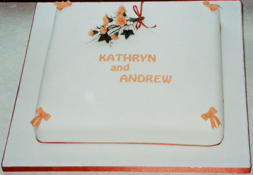 A single tier wedding cake with sugar flowers and bows.