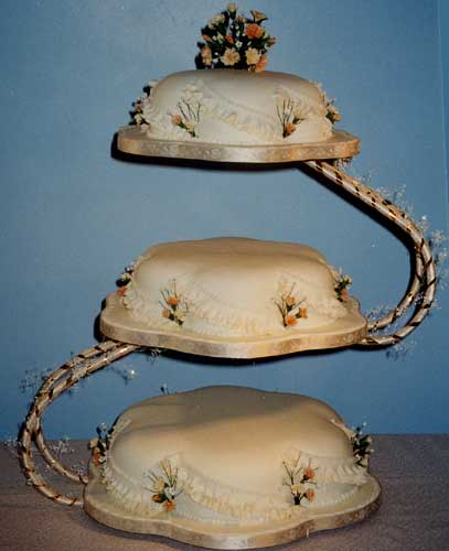 A modern three tier fruit wedding cake with swirling frills.