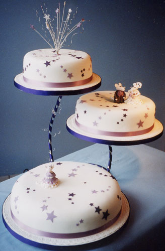 An elegant and modern 3-tier cake decorated with stars and three sugar crafted mice. The bottom tier is a fruit cake, and the top two tiers have a rich chocolate recipe.